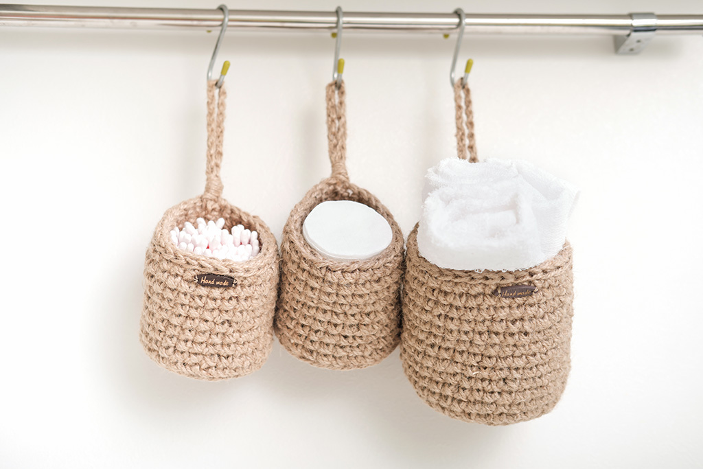 three wicker mini baskets hanging on a wall. toiletry storage in bathroom. eco natural jute hand made basket. cozy scandinavian style interior. zero waste storage concept, front view.