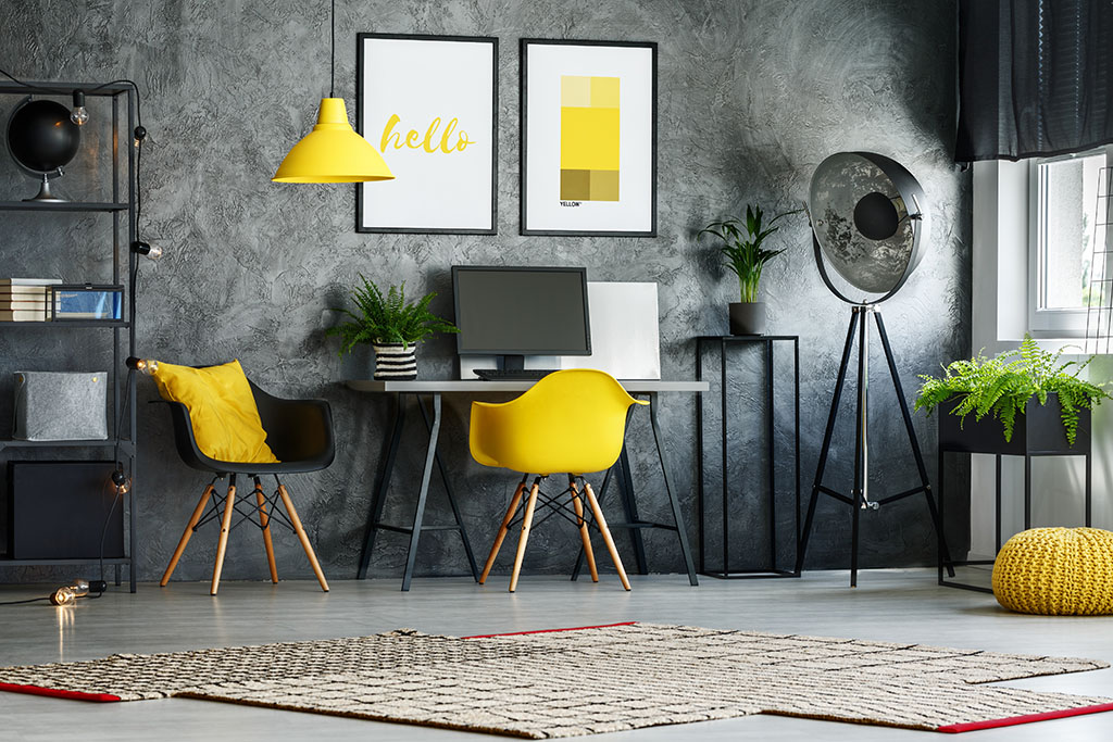 Yellow chair,pouf and designer lamp in stylish home office with posters on concrete wall, home remodeling chicago company